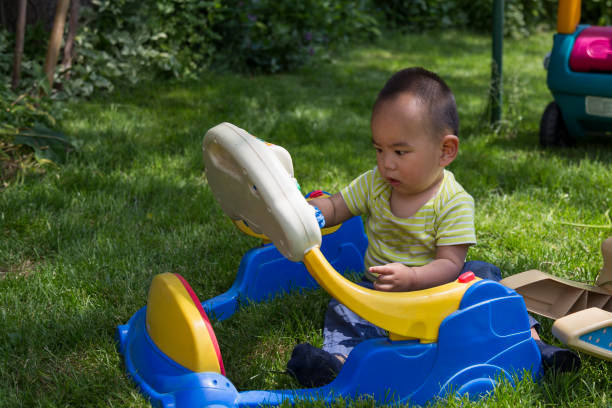 A little Chinese boy is playing toy on grassland in back yard.